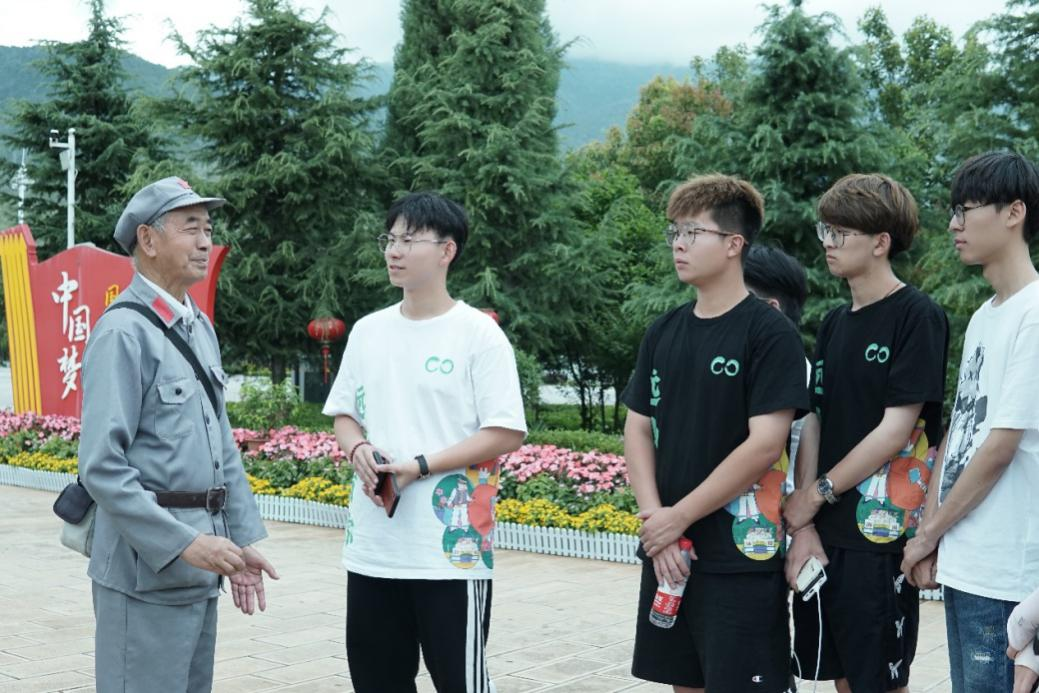实践队成员在鹤庆纪念碑广场聆听老党员讲述红军长征故事 实践队成员在鹤庆纪念碑广场聆听老党员讲述红军长征故事